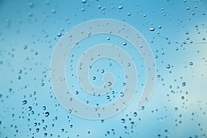 Water drops on the window, blue sky and clouds in the blurry background