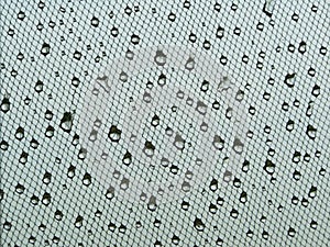 Water drops on window net mesh with cloudy sky on background