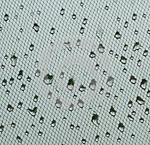 Water drops on window net mesh with cloudy sky on background