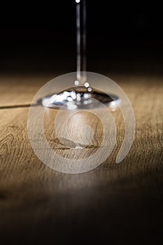 Water drops on a wooden table with blurry wineglass foot