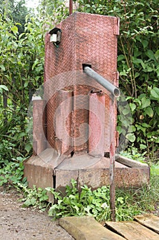 A water electric pump with a switch for pumping water from underground and pouring into vessel puted on wood boards in a dacha gar