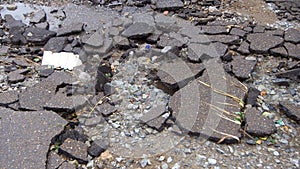 Water erosion of the road. Broken asphalt background. Danger hole, stone gray backdrop