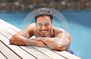 The water is excellent. Portrait of a handsome young man sitting in a pool.