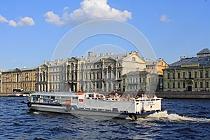 water excursion in the summer by boat on the rivers and canals of St. Petersburg. A group of tourists listen to an audio