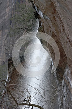 Water Falling Over Red Sandstone Cliffs with Branches in Winter