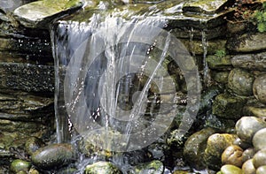 Water falling over stone wall in garden setting