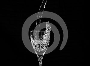 Water falling into a wine glass with a splash