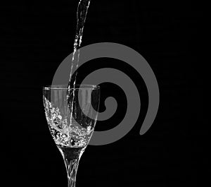 Water falling into a wine glass with a splash