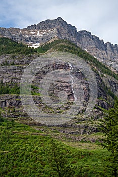 Water falls down mountains in Glacier National Park