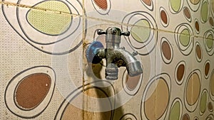 a water faucet attached to a ceramic wall with a polka dot pattern