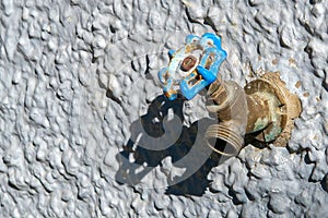 Water Faucet with a Blue Handle on a Textured Wall