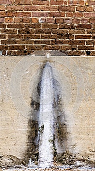 Water faucet eroding a concrete wall