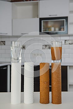 Water filter cartridge used and a glass of dirty water and new pure filter with a glass of clean water from domestic osmosis