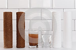 Water filter cartridge used and a glass of dirty water and new pure filter with a glass of clean water from domestic osmosis