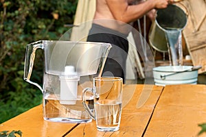 Water filter with a cup with a shirtless less man pouring water from a well