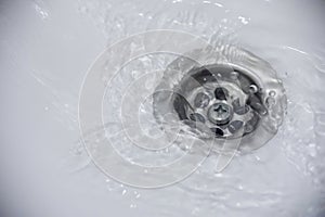 Water flow into drain in white bath