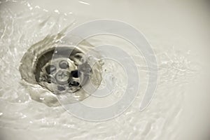 Water flow into drain in white bath