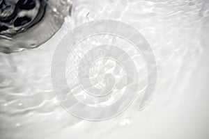 Water flow into drain in white bath