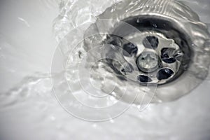 Water flow into drain in white bath