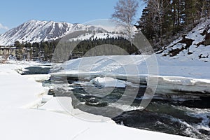 Water flow in the melting river among ice coast near mountains