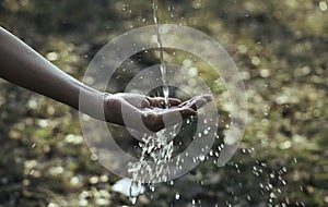 Water flow to hand in the garden on nature background