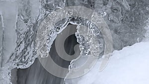 Water flow on waterfall in winter with ice form, close up