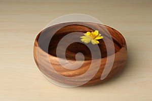 Water with flower in bowl on wooden table