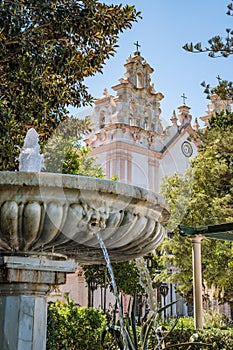 Water flowing in a blurred marble fountain with the bell tower of the Church of the Carmen in the background, CÃ¡diz SPAIN