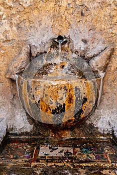 Water flowing from a faucet of a stone fountain