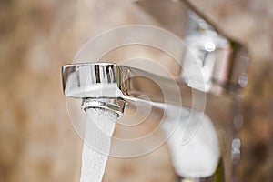 Water flowing faucet. Water tap with flowing water. Selective focus, shallow depth of field. Working water tap