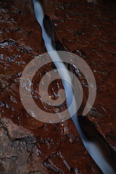 Water flowing through fissure in red rock, Zion National Park, Utah