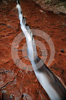 Water flowing through fissure in red rock, Zion National Park, Utah