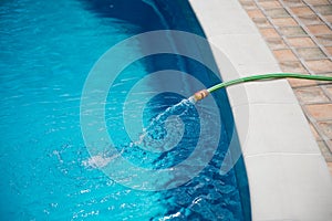 Water flowing from the hose into the pool, filling, servicing