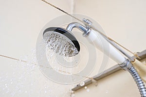 Water flowing from an old shower head with ceramic handle with limescale needed to be replaced or decalcified