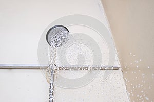 Water flowing from an old shower head with ceramic handle with limescale needed to be replaced or decalcified