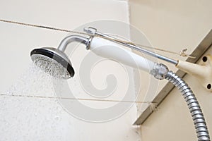 Water flowing from an old shower head with ceramic handle with limescale needed to be replaced or decalcified