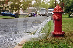 Water flowing from an open red fire hydrant is wet from the spray