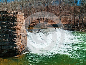 water flowing over a rock wall into a river in the fall