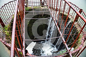 Water flowing into the round spillway on the dam