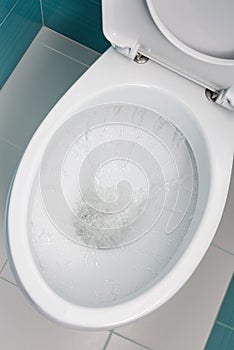 Water flowing into a white toilet