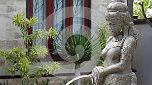 Water flowing from woman sculpture in the garden of balinese house. Bali, Indonesia. Good for a background.