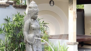 Water flowing from woman sculpture in the garden of balinese house. Bali, Indonesia. Good for a background.