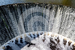 Water flows from a dam on the river. Spring in the village. Zagare, Latvia