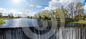 Water flows from a dam on the river. Spring in the village. Zagare, Latvia