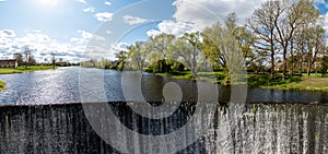 Water flows from a dam on the river. Spring in the village. Zagare, Latvia