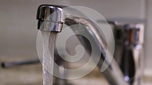 Water flows down from the kitchen faucet. Concept. Clean water flowing from a chrome tap in the kitchen.