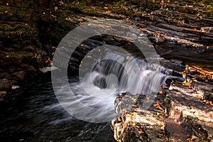 Water flows gently over rocks in Fall