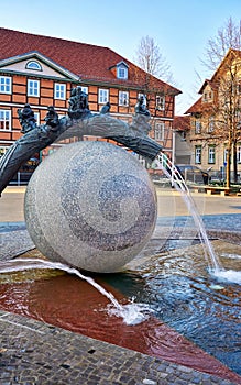 Water fountain in the form of a ball with a tree trunk and sculptures sitting on it. Wernigerode old town