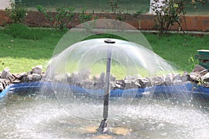 Water fountain in the garden with silky water effect and reflections of natural light