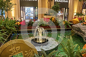 A water fountain and pool surrounded by lush green trees and plants, gold coins and colorful flowers, Chinese lanterns